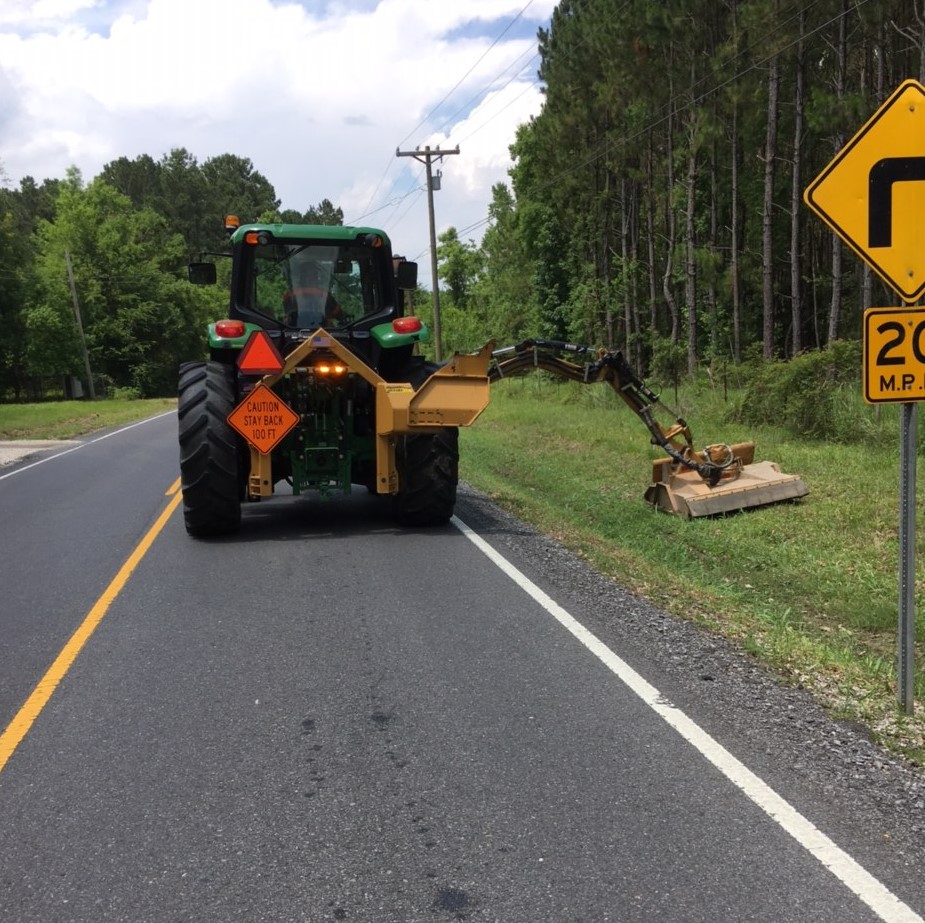 Public Works employees using boom mower on roadside