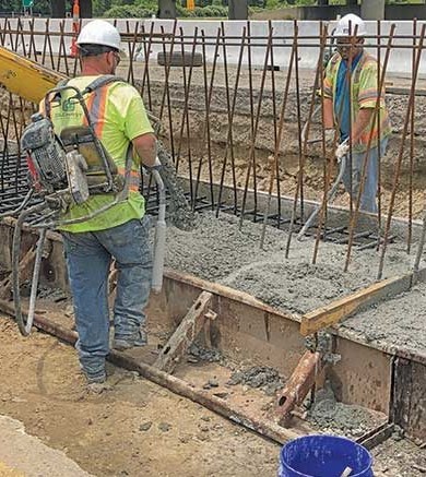 SMALL Workers pouring concrete for a road project